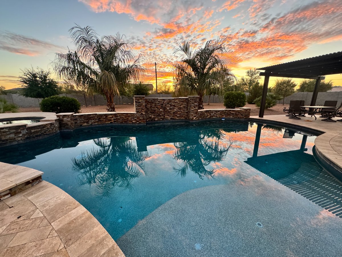 Beautiful desert sunset in an Arizona backyard with a palm tree, pergola / ramada and swimming pool