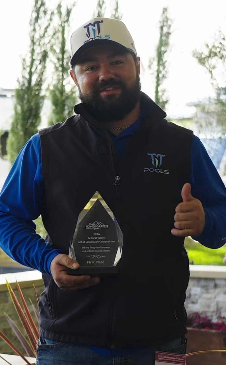 Man in blue and black WT Pools apparel holding a teardrop-shaped award trophy while giving thumbs up outdoors